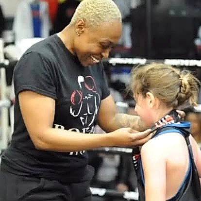 A coach awarding a medal to a young boxer